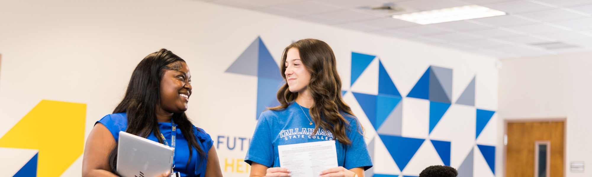 Student and Advisor walking through the advising center and talking.
