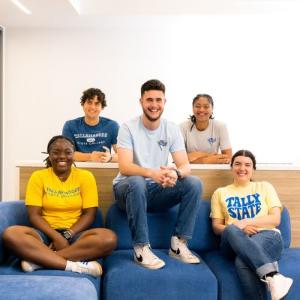 Five students sitting together and smiling toward the camera.