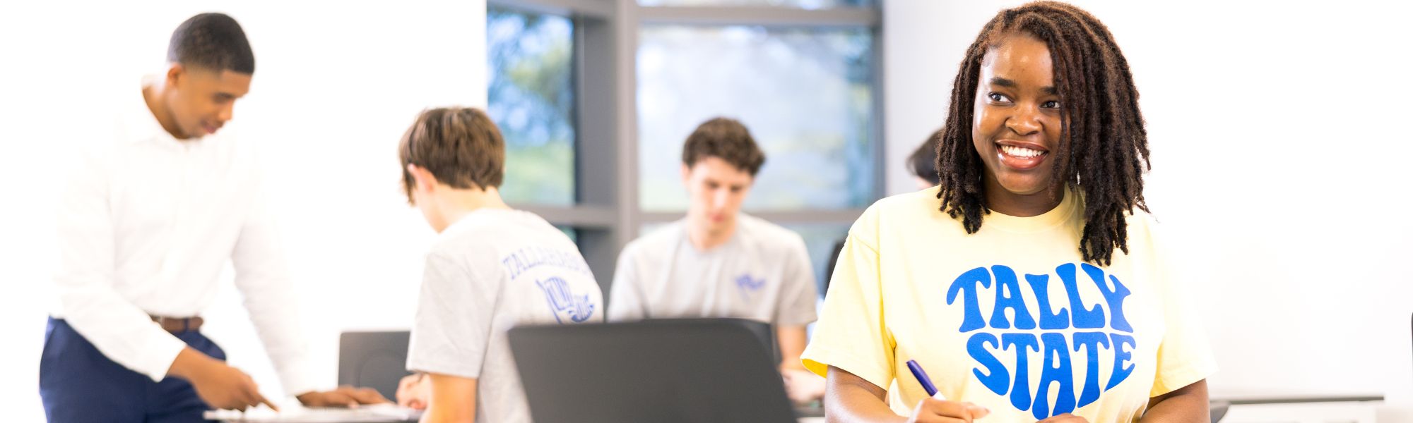 Several students studying together with a central student smiling for the camera.