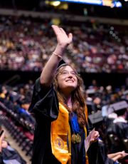 Graduating student waving up at her family.