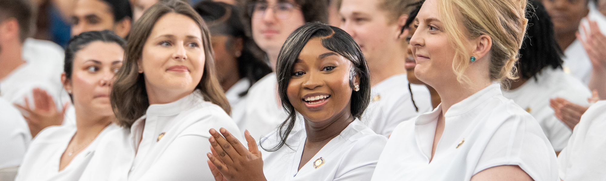 Nursing program graduates smiling during pinning ceremony.