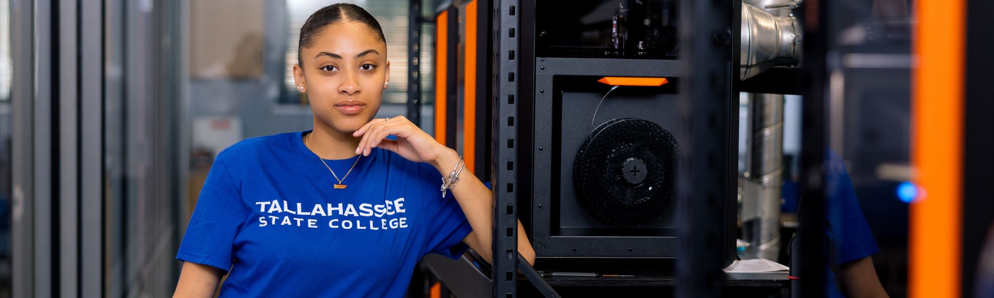 TSC student standing in front of row of 3D printers.