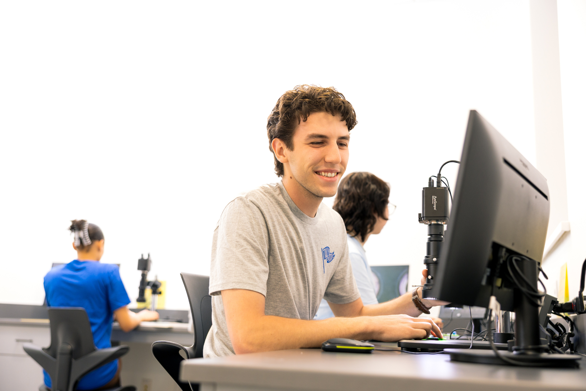 student using laptop and microscope in innovation lab