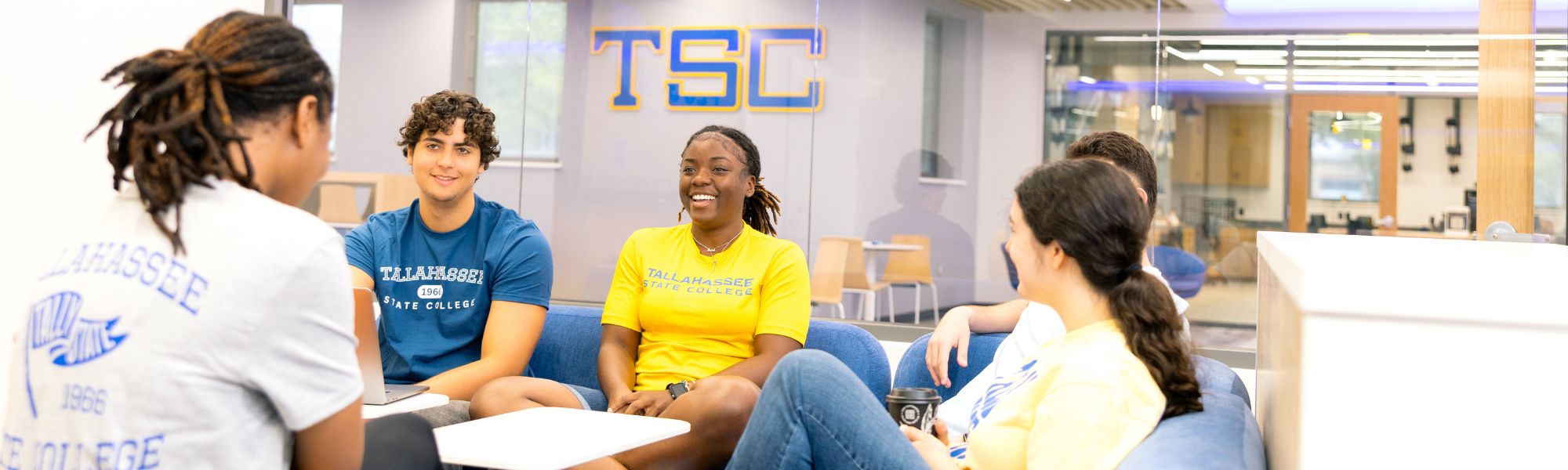 TSC student smiling in classroom with a dark background.
