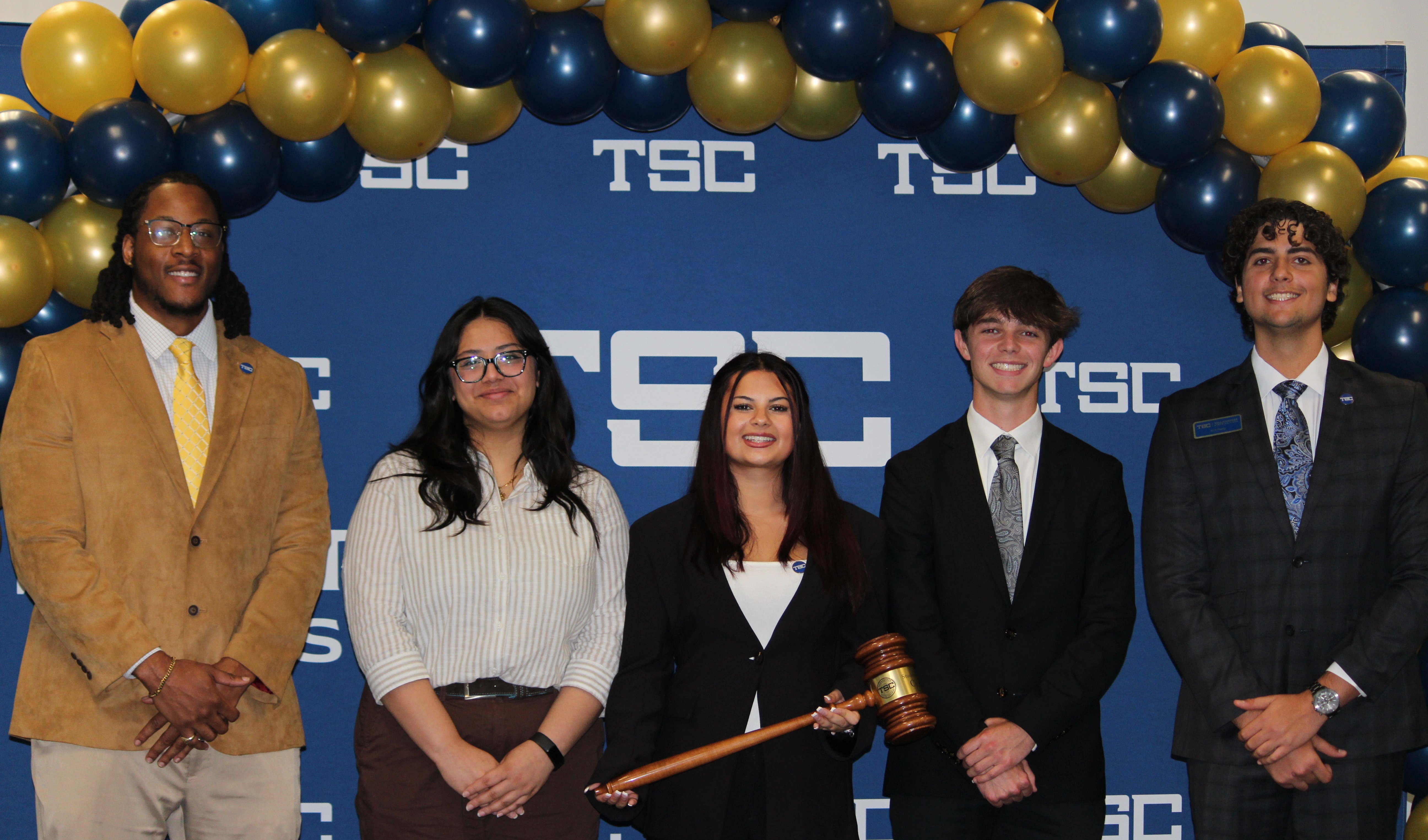 A group of five students smiling at a passing of the gavel event