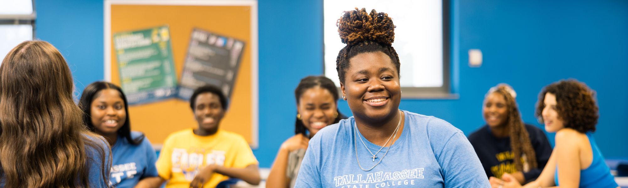 7 smiling students sitting in class and chatting.