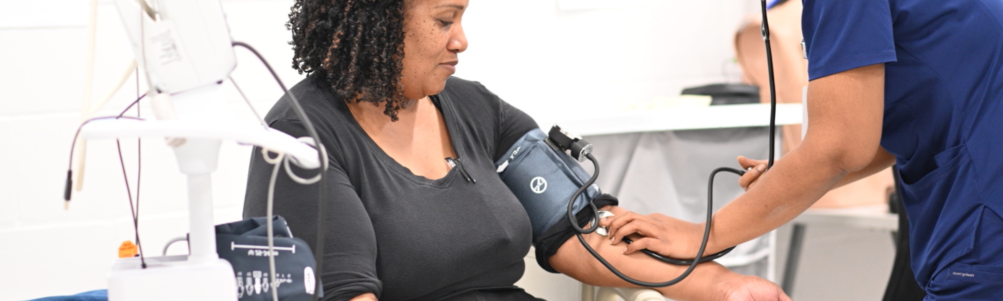 Medical assisting students practicing with blood pressure measuring equipment.